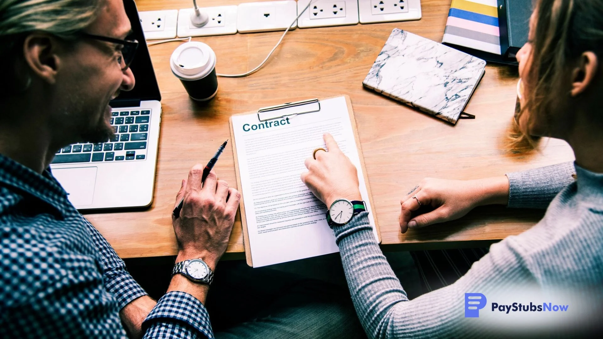 Two people discuss contract terms while looking at the printed contract on a clipboard