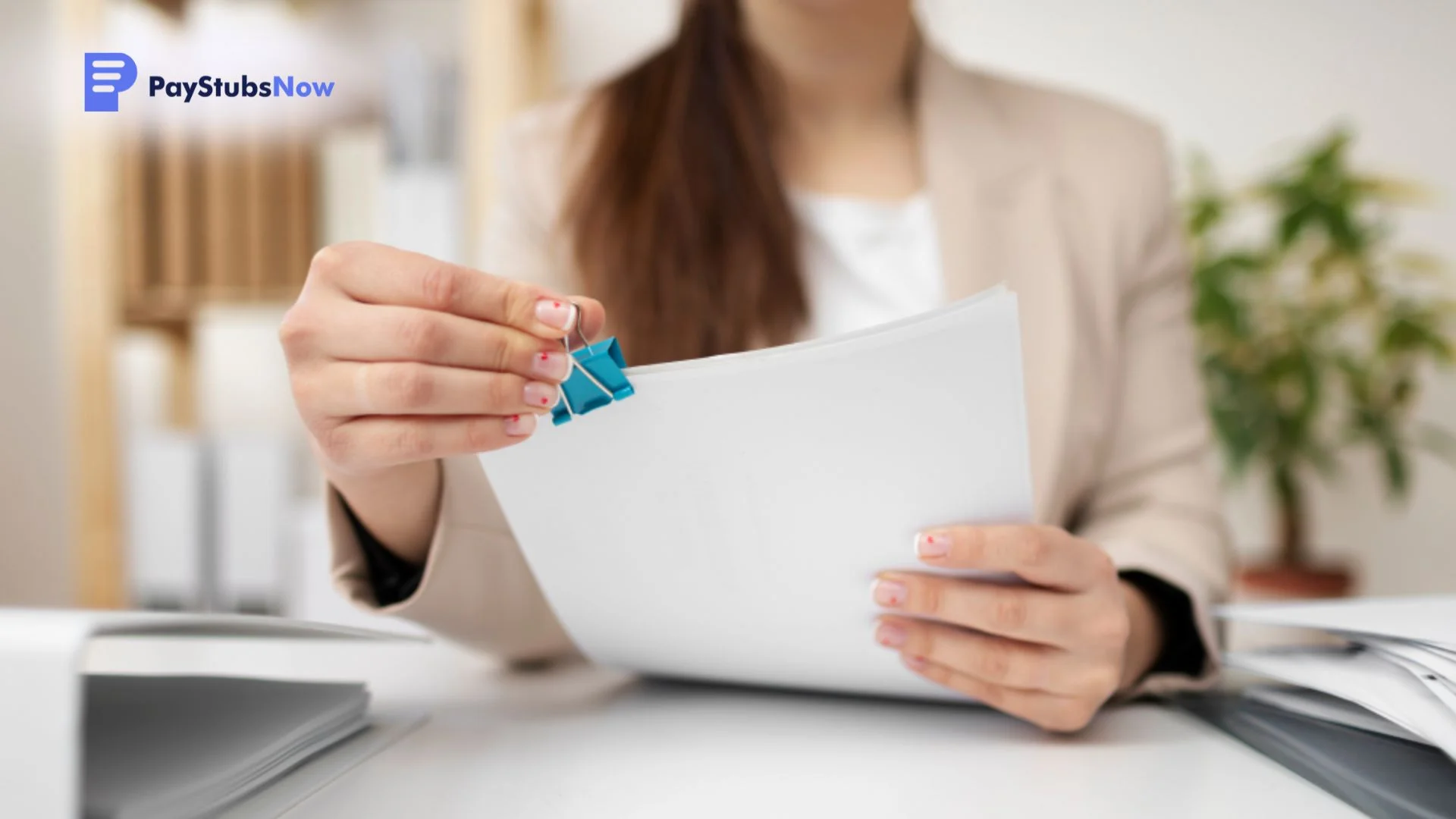 A corporate professional organizes and clips together a stack of papers at her desk.