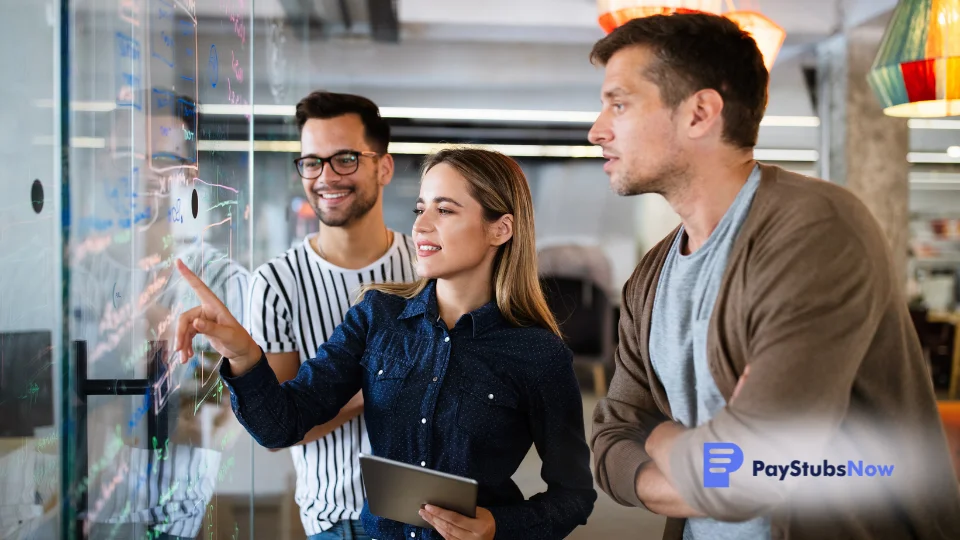 Three people looking at a whiteboard in an office