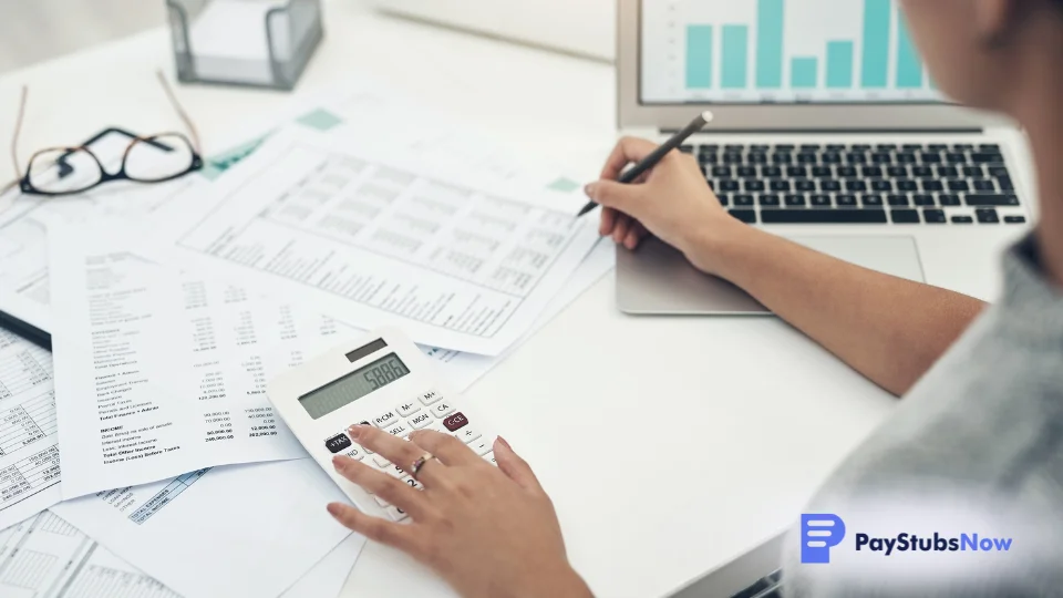 An HR professional reviews payroll documents using a pen and calculator