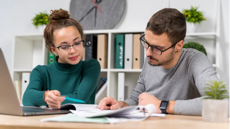 Two individuals at a desk looking through financial documents