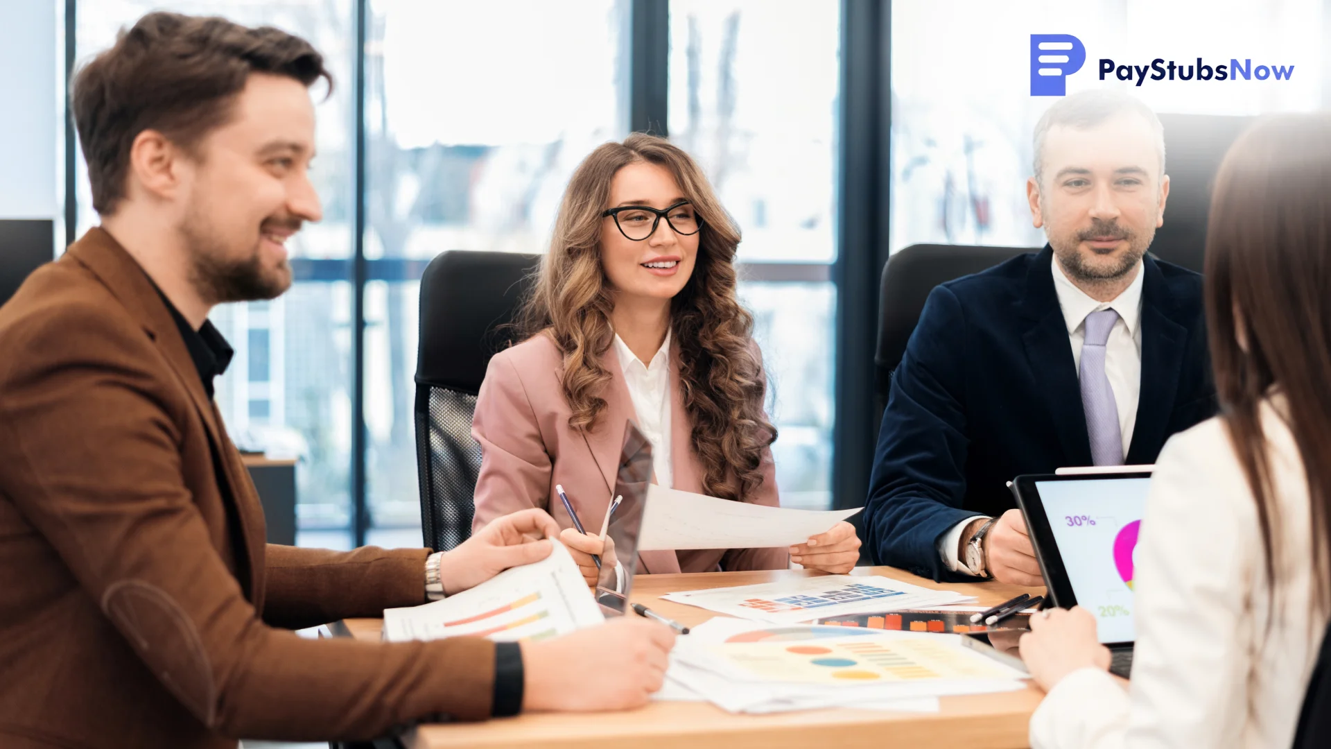 Four business professionals in a meeting reviewing charts and documents