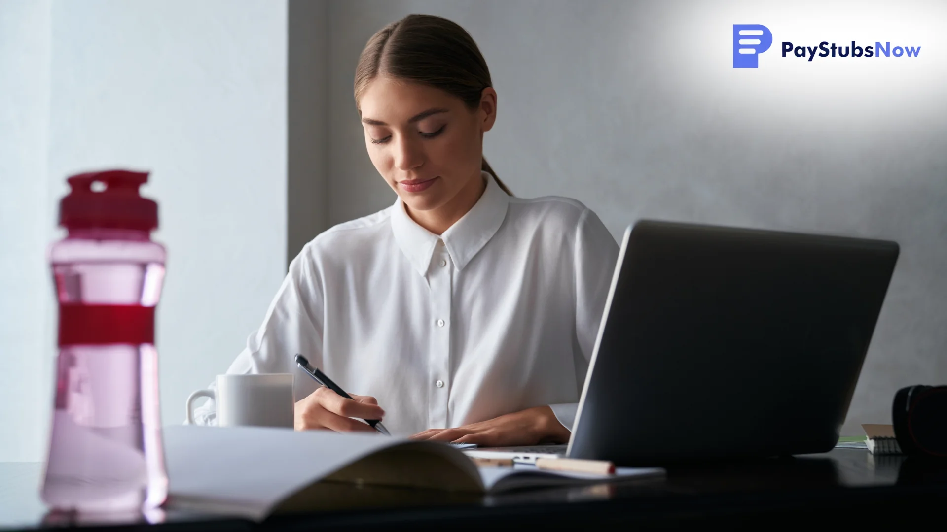 A focused professional writing at a desk with a laptop